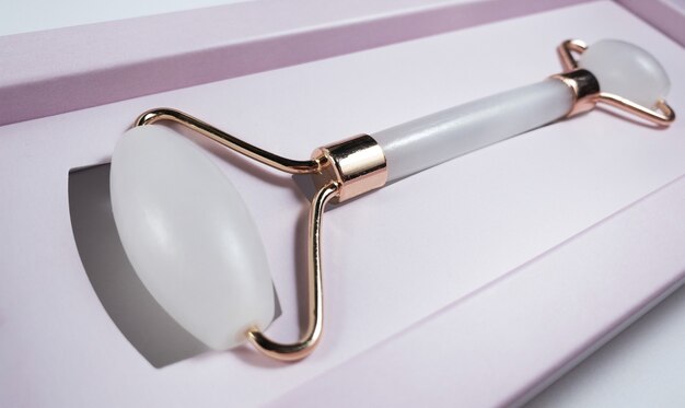 Белый массажный кварцевый ролик для лица крупным планом в розовой подарочной коробке, концепция красоты и ухода для женщин