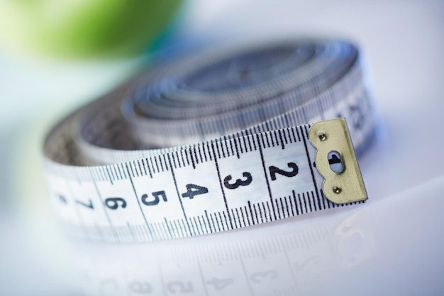 White measuring tape and apple on background. concept about diet