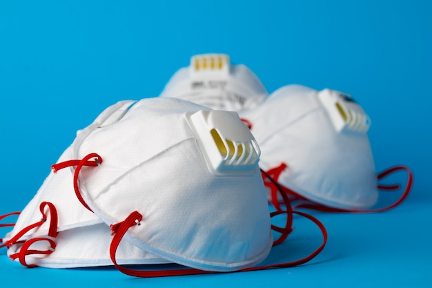 White medical face masks on blue background close up