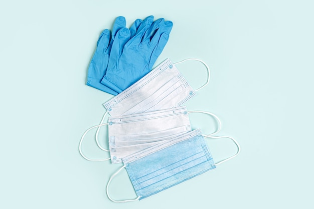 Белые медицинские маски и перчатки на синем фоне. Маска для защиты от вирусов, гриппа, коронавируса, COVID-19. Медицинское оборудование.