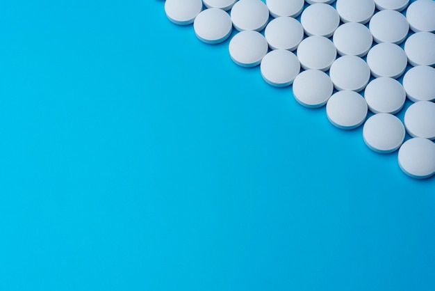 White medical pills on a blue background in the upper right corner