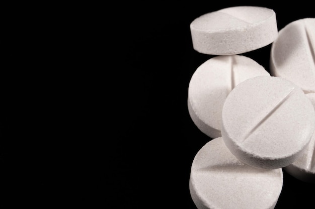 Белые медицинские таблетки и таблетки на черном фоне Крупным планом фото медицинских препаратов с копией пространства
