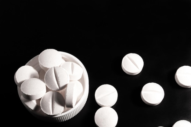 Белые медицинские таблетки и таблетки на черном фоне Крупным планом фото медицинских препаратов с копией пространства