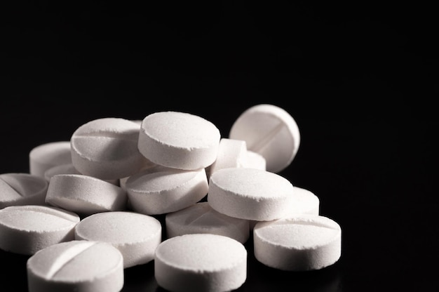 White medical pills and tablets on black background Closeup photo of medical preparations with copy space