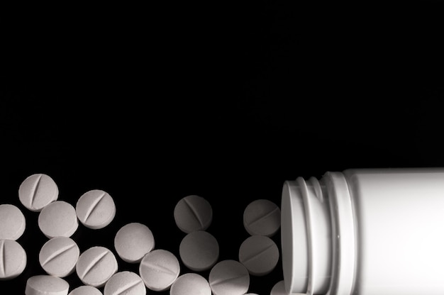 White medical pills and tablets on black background Closeup photo of medical preparations with copy space