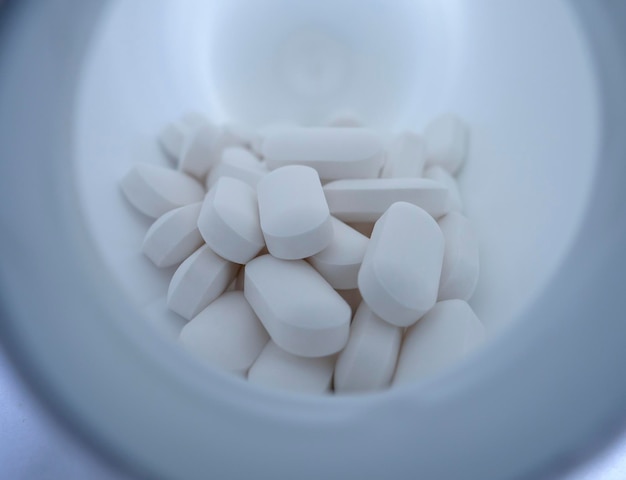 White medicinal pills are scattered from a bottle container close-up