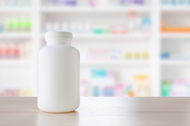 薬局のドラッグストアの棚が付いている木製のカウンターの白い薬瓶は、医薬品の背景をぼかす