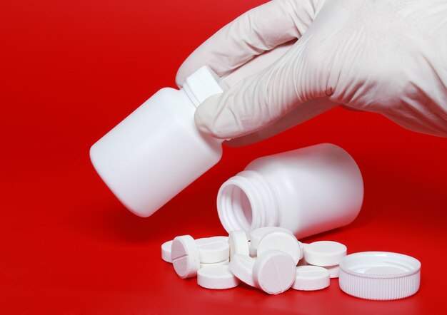 Белые бутылки медицины, цветные таблетки на цветном фоне.
