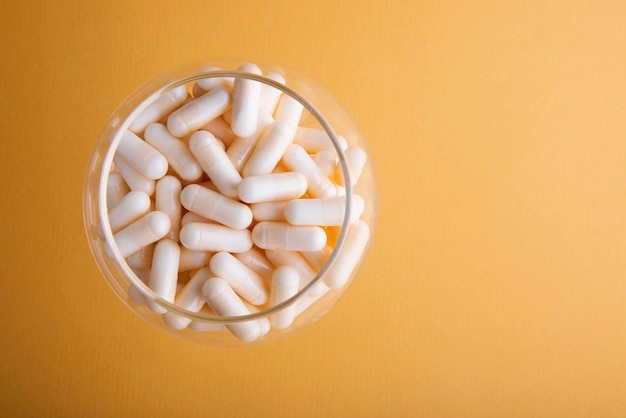 White medicine capsules on orange background