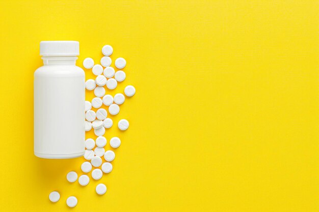 White medicine pills spilled from plastic pill bottle on yellow background medicine creative