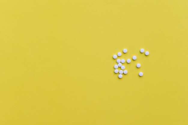 White medicine pills on yellow background