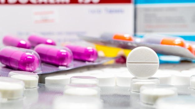 White medicine tablet among blur medicine packaging blurred background