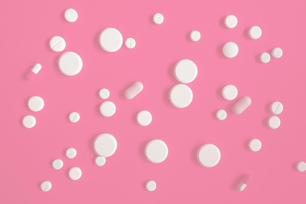 Foto medicinali o pillole bianche su sfondo rosa. prodotti dimagranti, vitamine, ormoni o sedativi. il concetto di salute delle donne.
