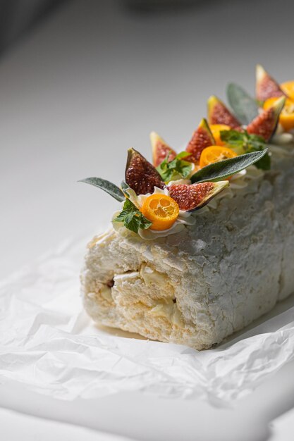 Photo white meringue cake with cream decorated with kumquat mint figs on parchment paper