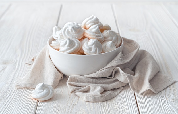 The white meringue cakes on the plate are wrapped in a linen napkin. Side view, horizontal.