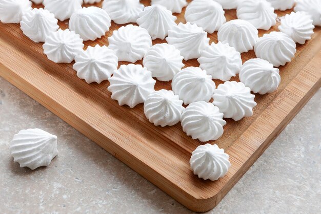 Photo white meringues on the wooden tray