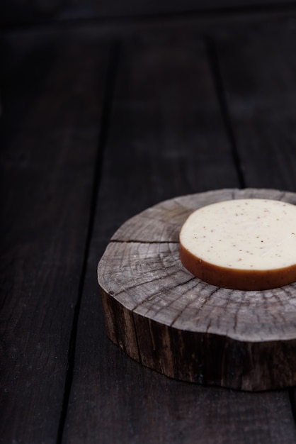 White milk cheese with seeds on a wooden end of a tree