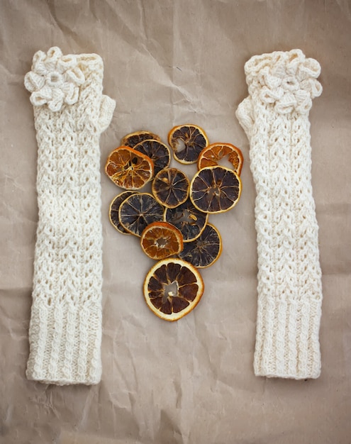 White mittens , dried orange slices and pink heart on paper background.