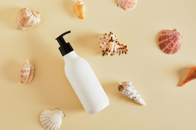 White mockup bottle for cosmetics without a label and seashells on a beige background