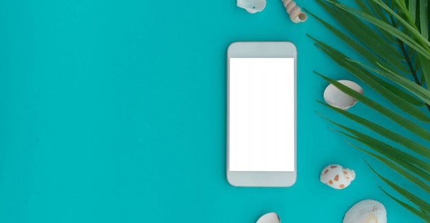 Foto smartphone mockup bianco con conchiglia e foglie su sfondo