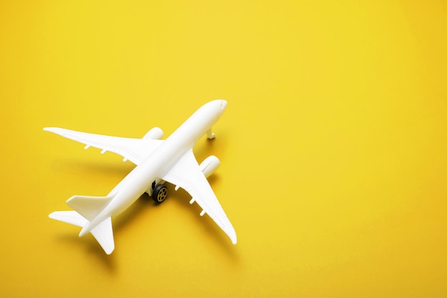 White model of passenger plane on yellow background travel concept