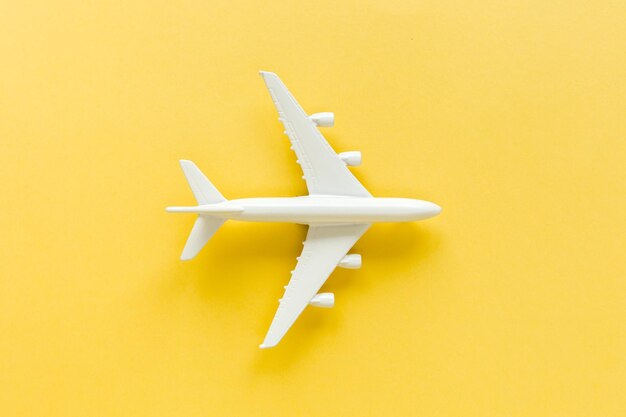 White model plane airplane on yellow background Top view flat lay