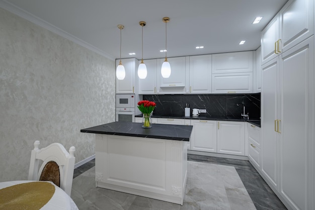 White modern domestic kitchen with island and black marble worktop