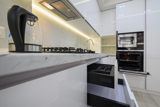 Белая современная кухня с убранными ящиками для плиты и микроволновой печи