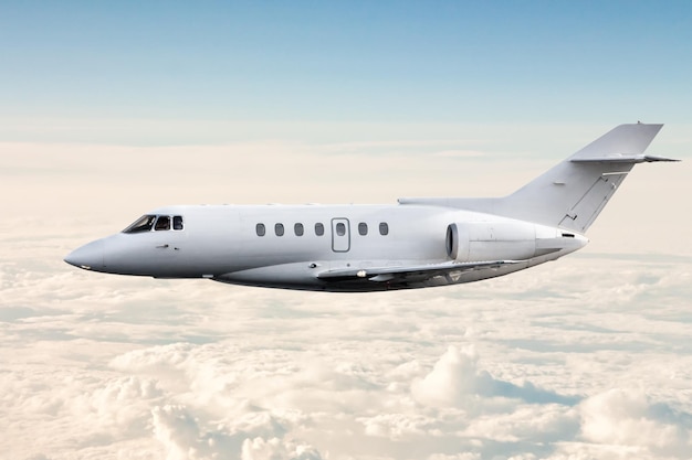 White modern luxury private jet flies in the air above the clouds