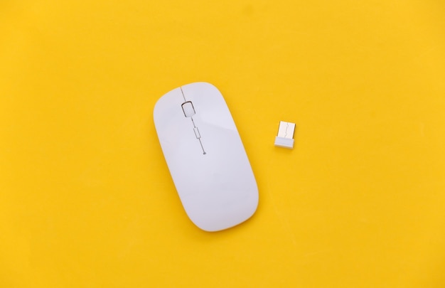 White modern wireless pc mouse on yellow background. Top view