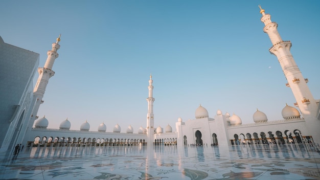 A white mosque in abu dhabi with a blue sky in the background