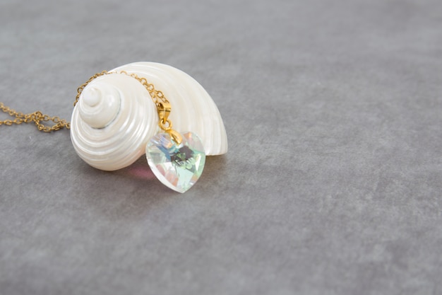 A white mother-of-pearl shell with a beautiful heart-shaped necklace and a beautiful precious stone