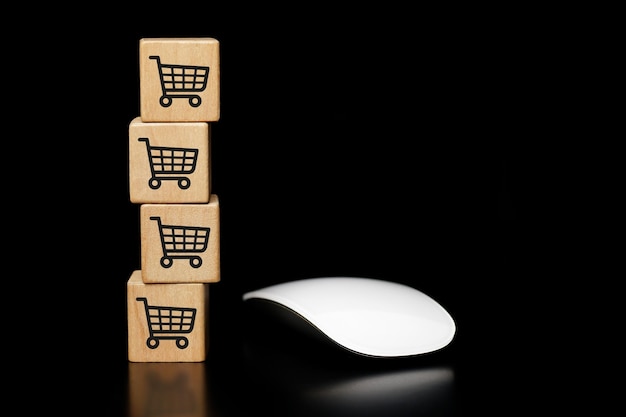 나무 큐브 쇼핑 카트 아이콘이 있는 흰색 마우스, 온라인 쇼핑. 어두운 배경에.