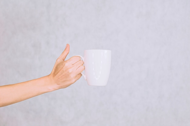 Tazza bianca per caffè, tè nella mano della ragazza. su uno sfondo bianco.