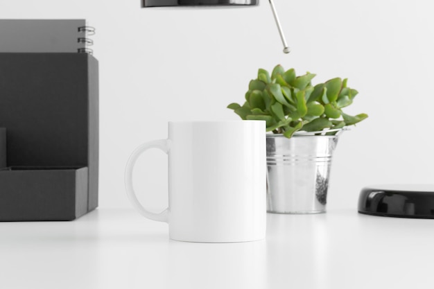 Photo white mug mockup with a lamp succulent plant and workspace accessories on a white table