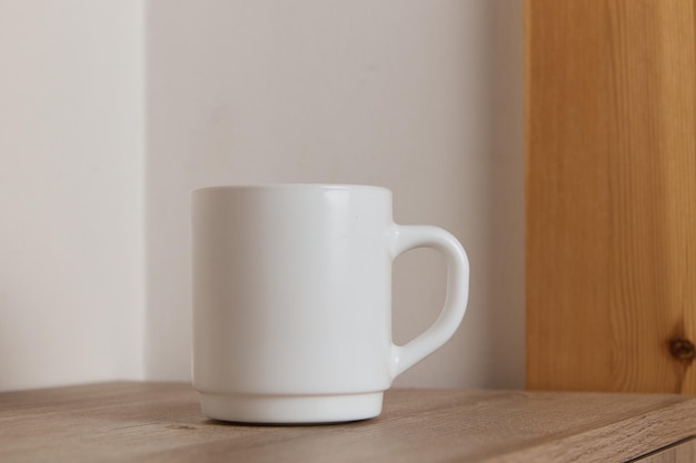 White mug for tea and coffee in on a wooden table closeup