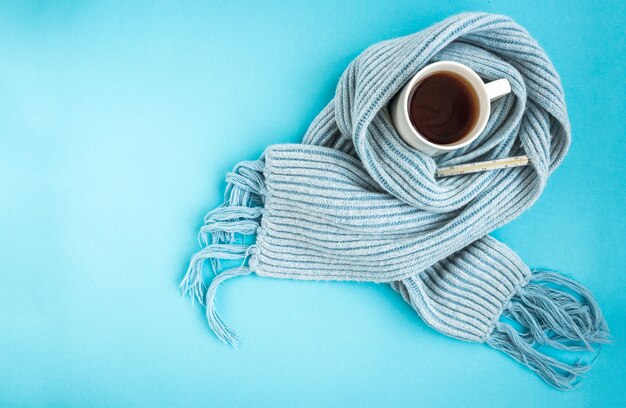 White mug of tea with blue scarf on blue.