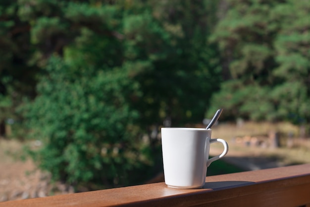 White mug with hot drink on the balcony