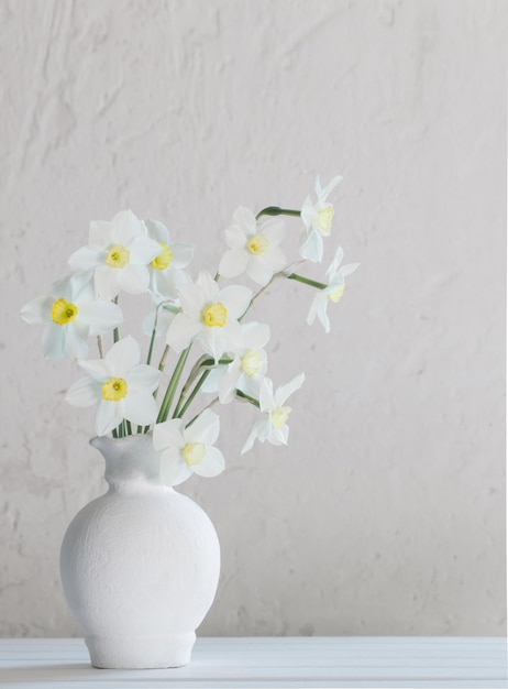 White narcissus in vase on wooden table