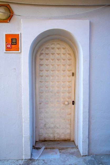 A white narrow door in a Turkish house with an arch and a window