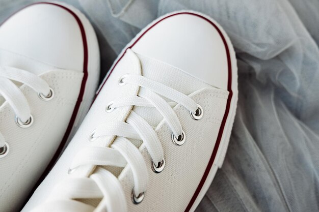 White new clean sneakers with white laces on a rubber sole on a gray tulle fabric