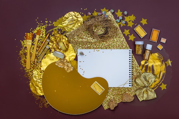 白いノートブックのモッケージは,明るい背景のテキストのための金色の文具と創造性のための材料のトップビュー カラフルな金色の芸術工芸