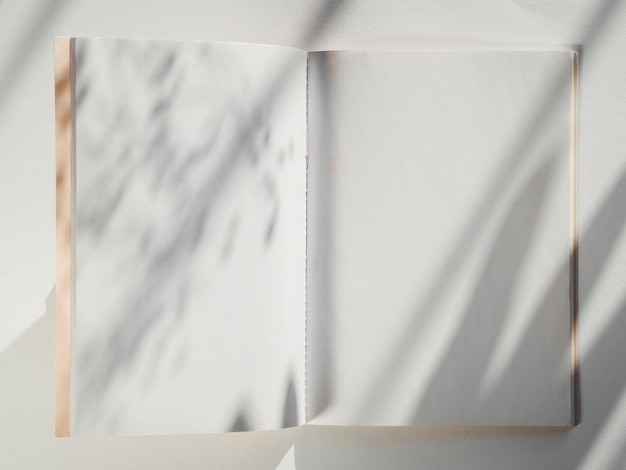 White notebook on a white background with leaf shadows