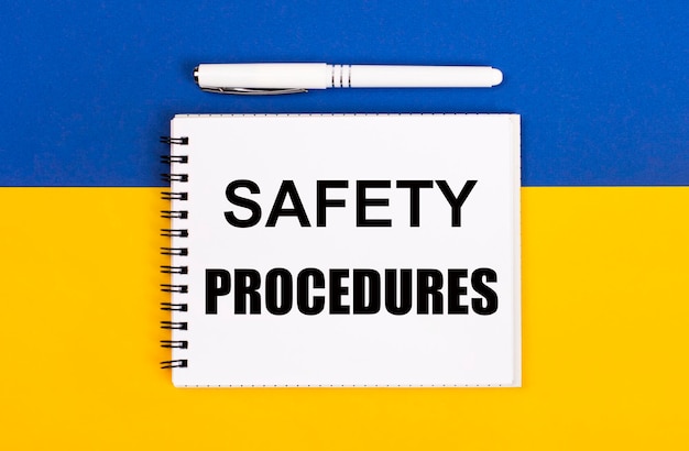 Photo a white notebook with the text safety procedures and a white pen on a blue and yellow background