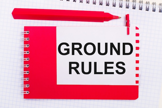 白いメモ帳、赤いペン、赤いメモ帳、白い紙に「GROUNDRULES」というテキストが表示されます