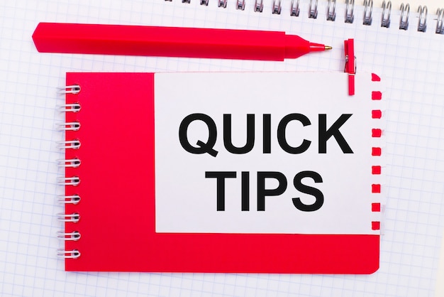 On a white notepad, a red pen, a red notepad and a white sheet of paper with the text QUICK TIPS