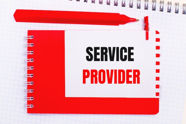 흰색 메모장에 빨간색 펜, 빨간색 메모장 및 SERVICE PROVIDER라는 텍스트가 있는 흰색 종이