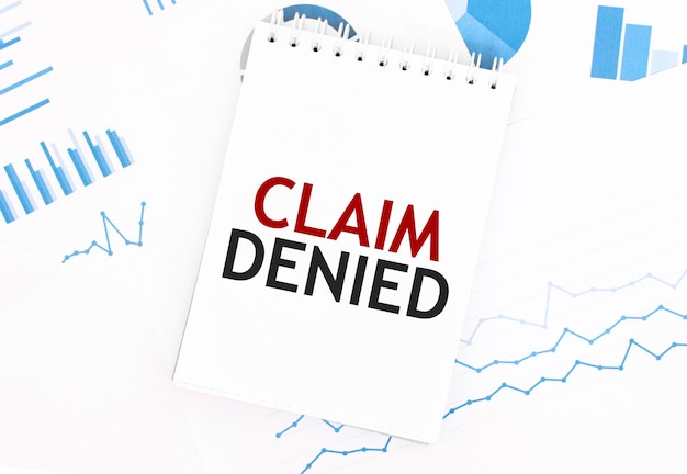 White notepad with text CLAIM DENIED on the financial documentation Finance and business concept