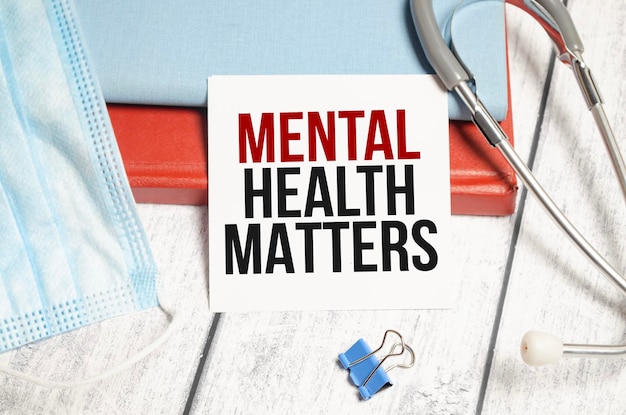 White notepad with the words mental health matters and a stethoscope on wooden background