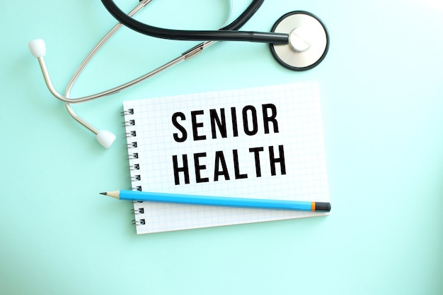 SENIORHEALTHという言葉と青い背景に聴診器が付いた白いメモ帳